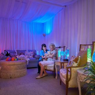 A cozy lounge area with soft lighting and comfortable seating, where children are enjoying their time surrounded by toys.