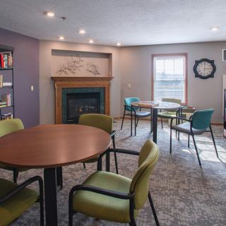 A cozy room with tables and chairs, featuring a fireplace and a window.