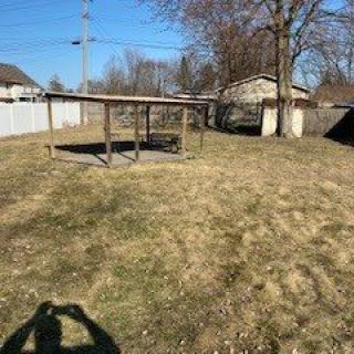 A sunny backyard with a shade structure and a small shed in the background.