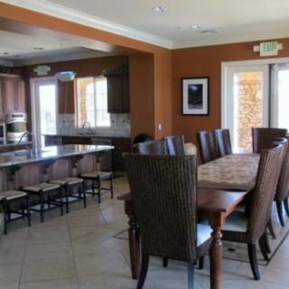 A modern kitchen and dining area with a large wooden table, chairs, and a countertop with stools.