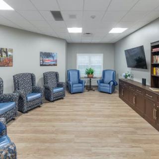 A modern waiting room with comfortable chairs, a television, and a bookshelf.
