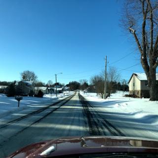 A serene winter scene with a snow-covered road and clear blue skies.