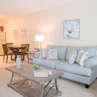 A cozy and modern living room with a sofa, coffee table, and adjacent dining area.