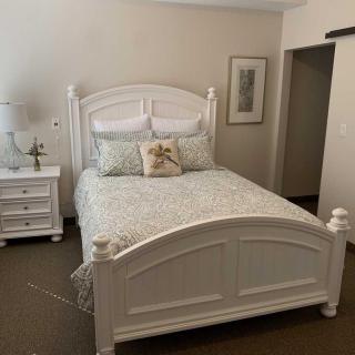 A cozy bedroom with a white wooden bed and matching nightstand.