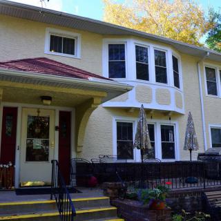 A charming two-story house with a front patio and stairs leading to the entrance.