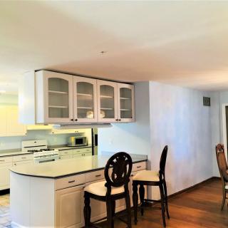 A modern kitchen with bar stools and an open layout connecting to the dining area.