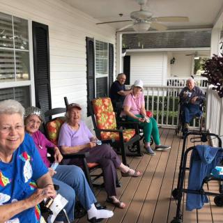 A group of elderly individuals relaxing on a porch.