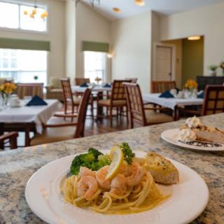 A plate of pasta with shrimp and broccoli in a restaurant dining area.
