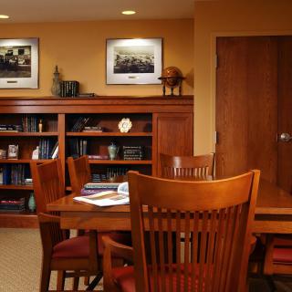 A wooden-furnished office conference room with a meeting table and bookshelves.