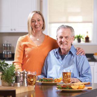 A smiling couple enjoying a meal together in their kitchen.