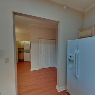A kitchen interior with a refrigerator and wooden flooring.