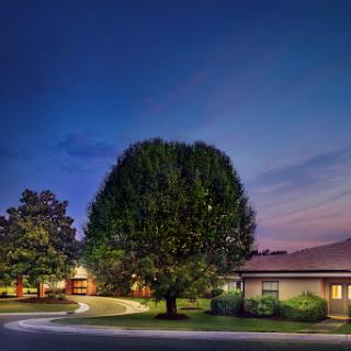 A serene residential scene at twilight, featuring a well-maintained house surrounded by lush greenery.