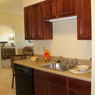 A cozy kitchen area showcasing dark wood cabinets, a clean countertop, and essential appliances.
