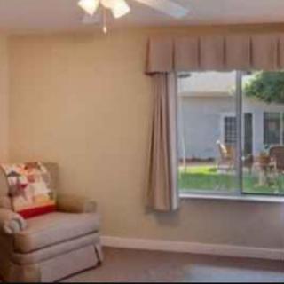 A cozy living room with a chair and large window overlooking the backyard.