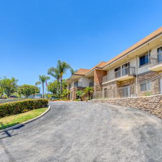 A sunny view of a building with a driveway lined by palm trees.