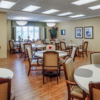 A neatly arranged dining room with multiple tables and chairs, featuring warm lighting and decor.