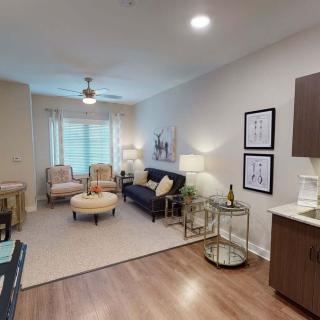 A modern living room with stylish furniture and decor, featuring a sofa, chairs, and wood flooring.