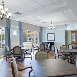 A spacious dining room with elegant chandeliers, comfortable chairs, and large windows providing natural light.