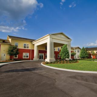 A modern building with a prominent entrance and well-maintained landscaping under a clear blue sky.