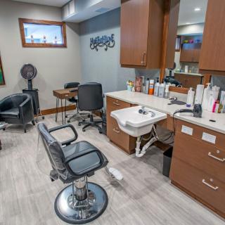 A modern hair salon interior featuring a styling chair, sink, and various hair products.