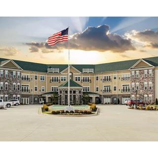 A large, multi-story building with an American flag in front under a dramatic sunset sky.