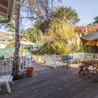 A sunny outdoor deck with patio furniture surrounded by trees, perfect for relaxation.