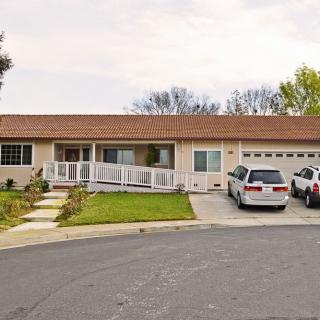 A suburban single-story house with a driveway and two cars parked in front.