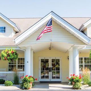 A charming house entrance adorned with an American flag and vibrant flowers.