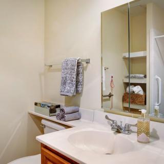 A tidy bathroom with a sink, mirror, and neatly arranged towels.