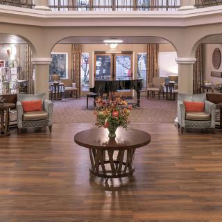A spacious and elegantly decorated lobby featuring a grand piano and floral centerpiece.
