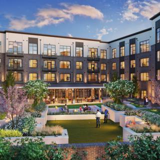 A modern apartment complex with a landscaped courtyard in the evening.