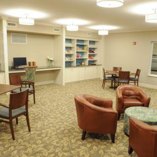 A cozy lounge area with bookshelves, tables, and chairs.