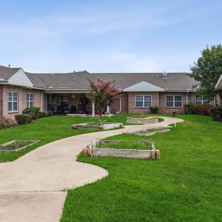 A single-story residential building with a well-maintained lawn and winding pathway.