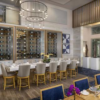 A luxurious dining room with elegant chandeliers and a modern wine storage display.
