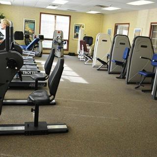 A gym with various fitness equipment and exercise machines lined up.