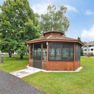 A charming wooden gazebo surrounded by lush greenery, perfect for relaxation and gatherings.