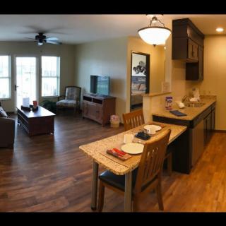 A cozy open floor plan living room and kitchen with wood flooring.