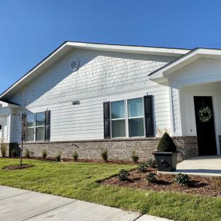 A single-story house with a well-kept lawn and front porch under a clear blue sky.