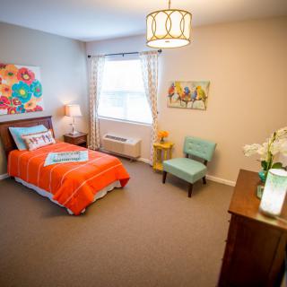 A cozy bedroom with a single bed adorned with colorful bedding and modern decor.