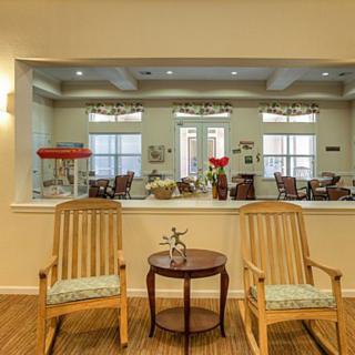 A cozy seating area with two wooden chairs and a small table in front of a large interior window.