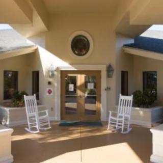 Entrance of a building with rocking chairs and potted plants.