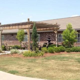 A landscaped area featuring a building with a pergola and a fountain.