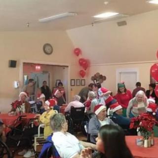 A festive holiday party with people wearing Santa hats and enjoying decorations.