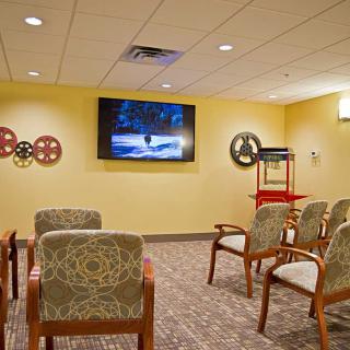 A cozy waiting room with chairs facing a television on the wall.