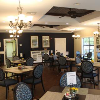 An elegant and well-decorated dining area with multiple tables and chairs, adorned with chandeliers.