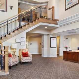 A spacious lobby featuring a staircase, reception desk, and modern furnishings.
