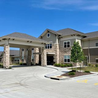 A modern residential building with a stone facade and landscaped surroundings.