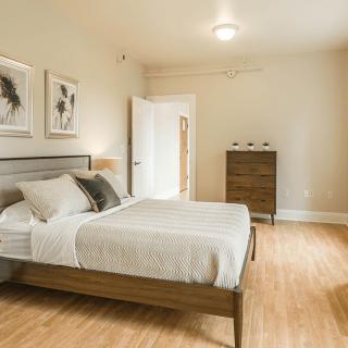 A modern and minimalist bedroom with neutral tones and wooden flooring.
