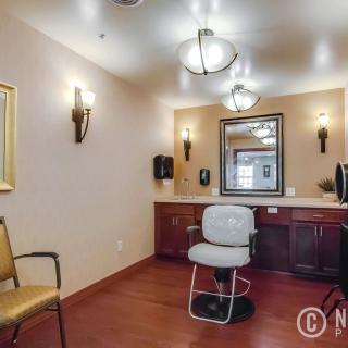 An empty salon room featuring a chair, mirror, and warm lighting.