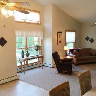 A cozy living room with a sofa, armchair, and large window providing natural light.